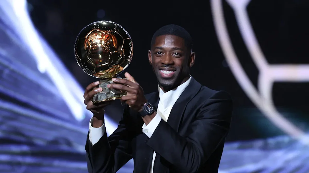 Trofi Ballon d'Or emas dengan latar belakang panggung penghargaan dan sorotan lampu
