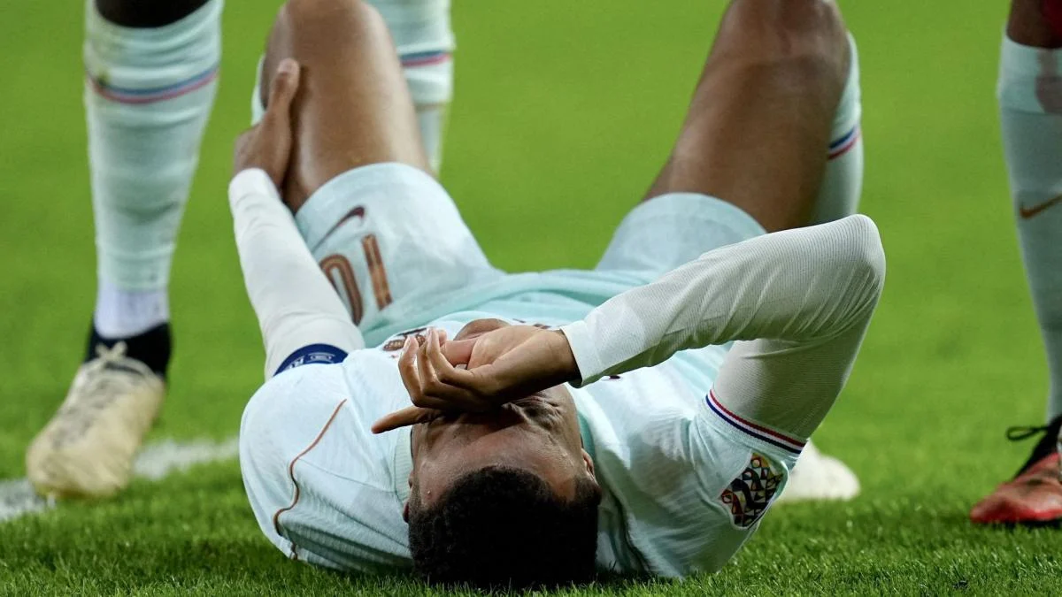 Kylian Mbappe berseragam Prancis berjalan meninggalkan lapangan sambil memegang lutut kirinya