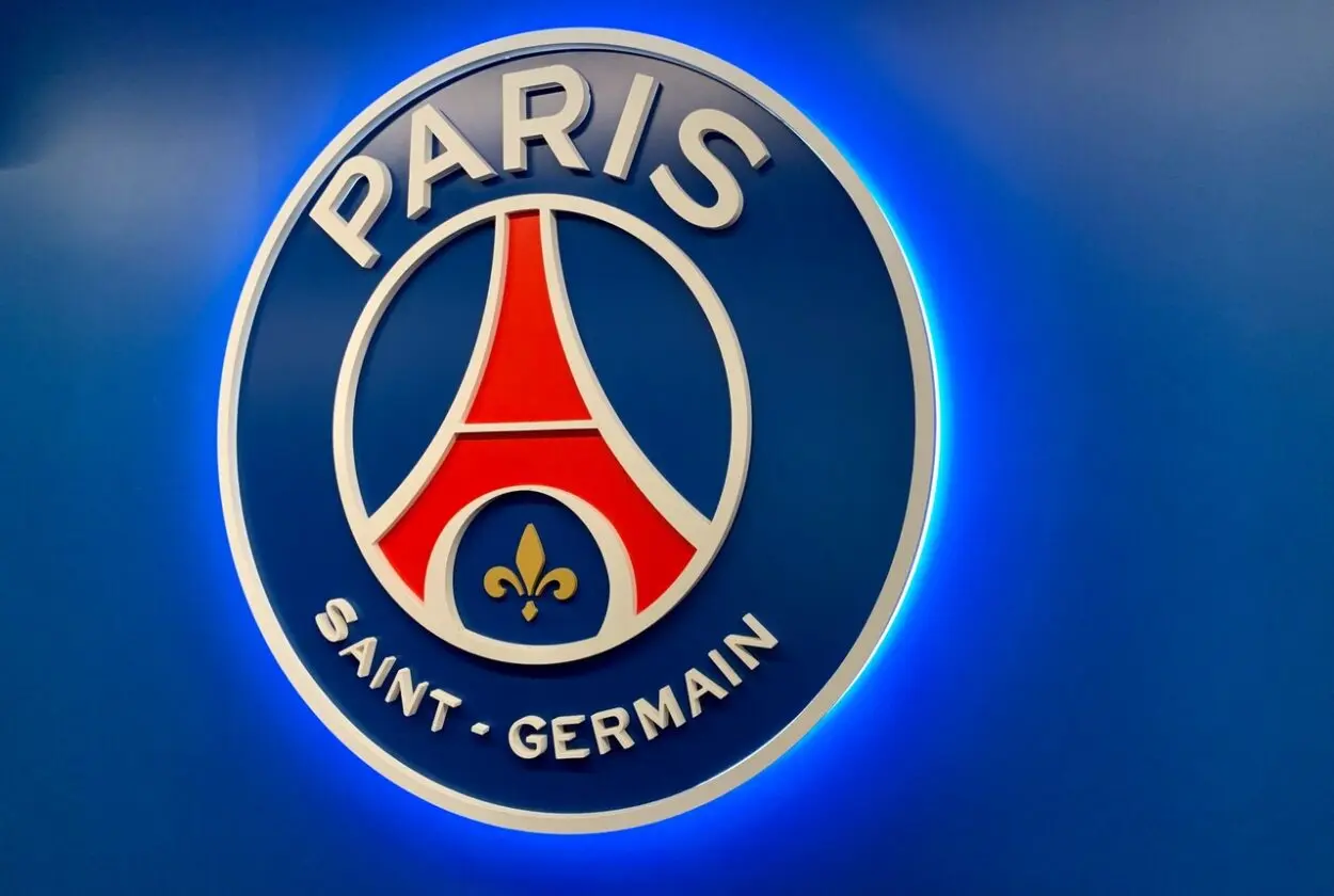 Logo PSG dengan latar belakang tribun stadion Parc des Princes